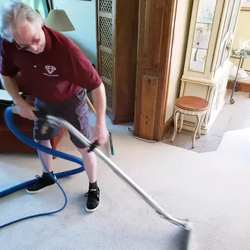 Crystal Clean technician running a hot-water extraction wand across a carpet